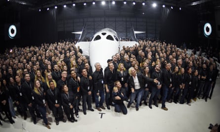 Sir Richard Branson poses with employees in front of Virgin Galactic’s new spaceship.