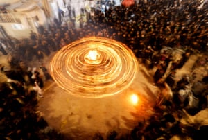 Optical illusion of a ring of light formed by moving torches, surrounded by a crowd
