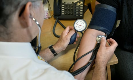 A doctor checks a patient’s blood pressure.