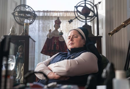 Sister Michael sits with arms crossed in a room filled with statues and antique armillary spheres