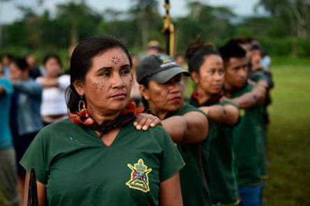 Lines of Indigenous guards with painted designs on their faces stand in lines with their left hand on the shoulder of the person in front
