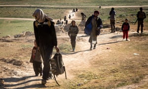 Civilians who fled the fighting in the city of Baghuz arrive at a screening point in Syria