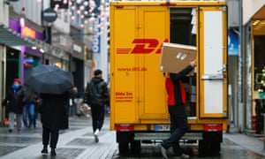 Seorang karyawan grup pos dan logistik Jerman DHL membawa sebuah kotak di Cologne, Jerman.