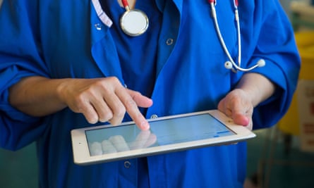 A doctor on a ward checks a patients’ records on an iPad.
