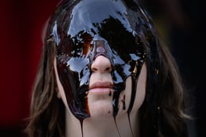 A woman’s face with a dark oil-like substance poured over it