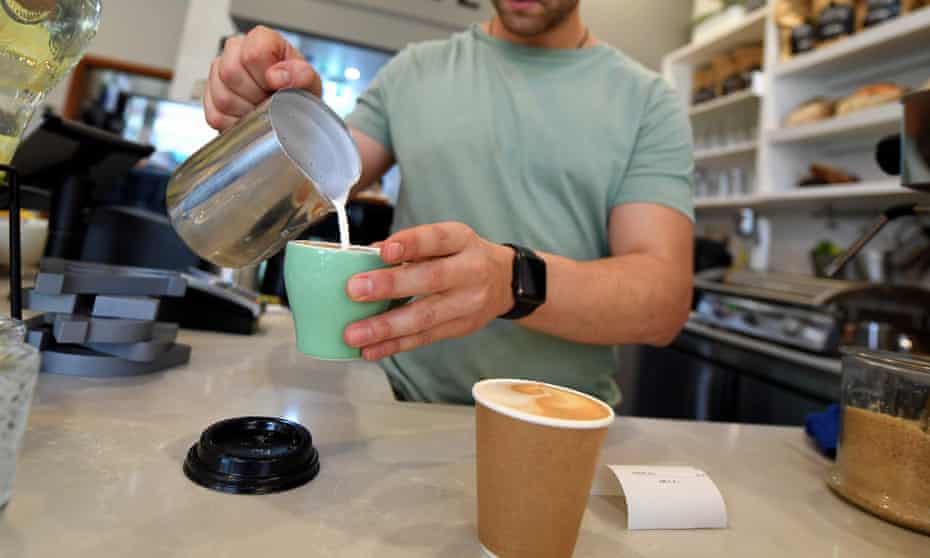 A barista is seen prepairing a coffee at a cafe