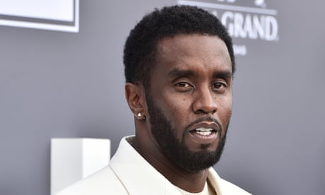 a man in a white suit looks into the camera