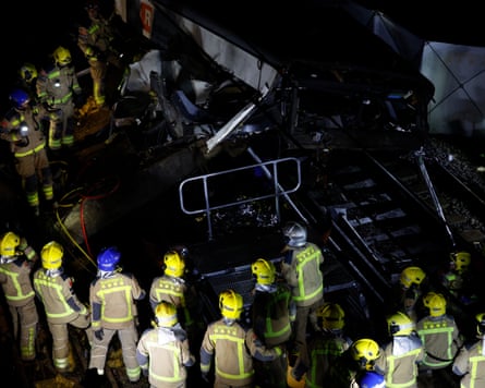 Numerous firefighters in hi-vis clothing at the scene of a train wreck.