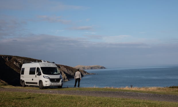 A campervan parked with a sunlit view of the sea at Cardigan Bay