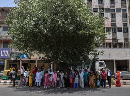 A crowd of people on a street under a tree