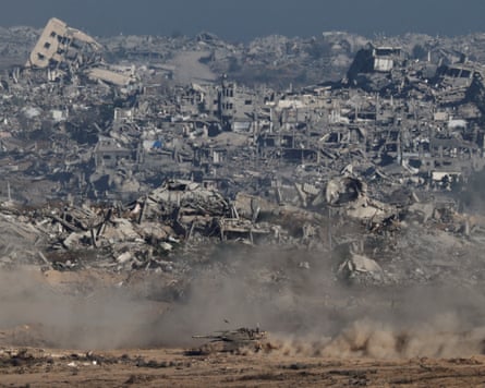 An Israeli tank at the bottom of the picture, as ruined buildings fill the hillside behind in Gaza.