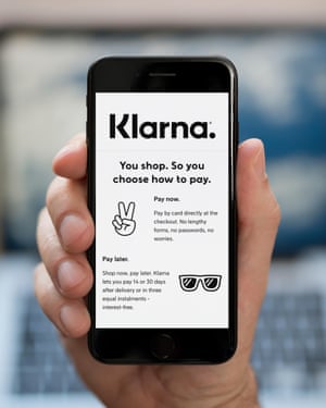 A man looks at his phone, which displays the Klarna logo