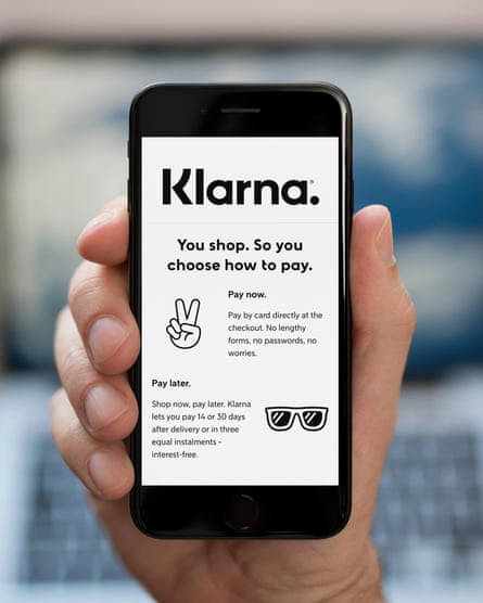 A man looks at his phone, which displays the Klarna logo