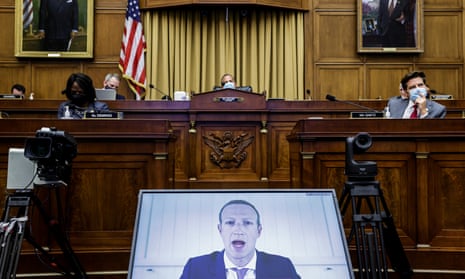 Mark Zuckerberg on a video screen facing the camera with members of a congressional committee in masks in the background