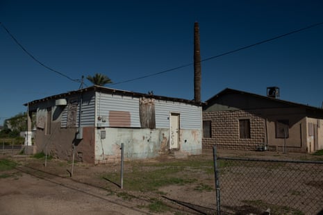 An image of two houses – one is covered by tin sheets, the other has a brown roof