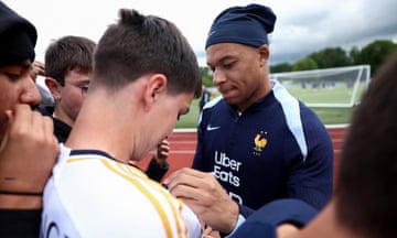 Kylian Mbappé signs a fan’s Real Madrid shirt at France training.