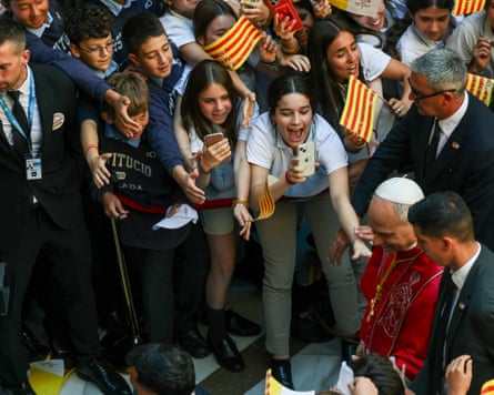 People reach out to the pope and wave flags as he walks through a crowd