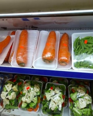 One carrot caught in a styrofoam tray wrapped with plastic