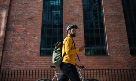 a man wearing a backpack and walking with a bicycle and smartphone