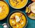 Overhead view of bowls of brown butter pumpkin soup topped with cream, seeds, and chilli oil