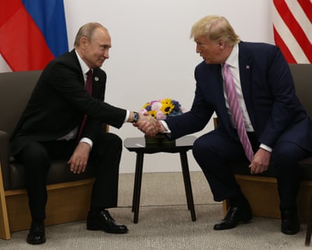 A seated Trump and Putin shake hands