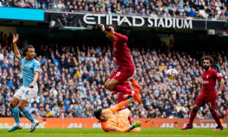 Liverpool's Cody Gakpo jumps over Manchester City's goalkeeper Ederson.
