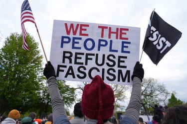 a person holds a sign that reads ‘we the people refuse fascism’