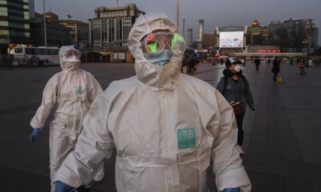 People wear protective masks and suits as they arrive at Beijing Railway Station on 13 March.