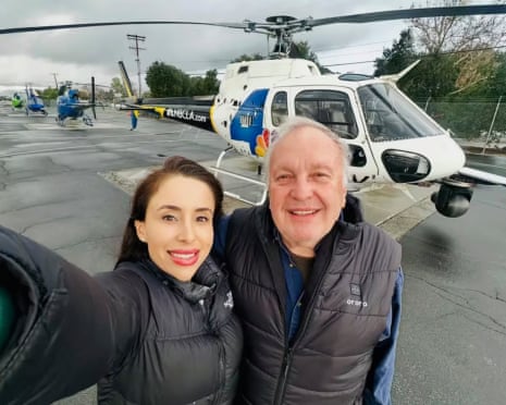 a woman and a man smile near a helicopter