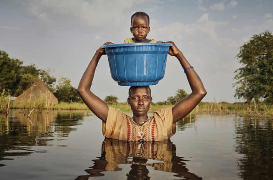 Nyalong Wal, 36, carries her daughter Nyamal Tuoch, 2, to dry land