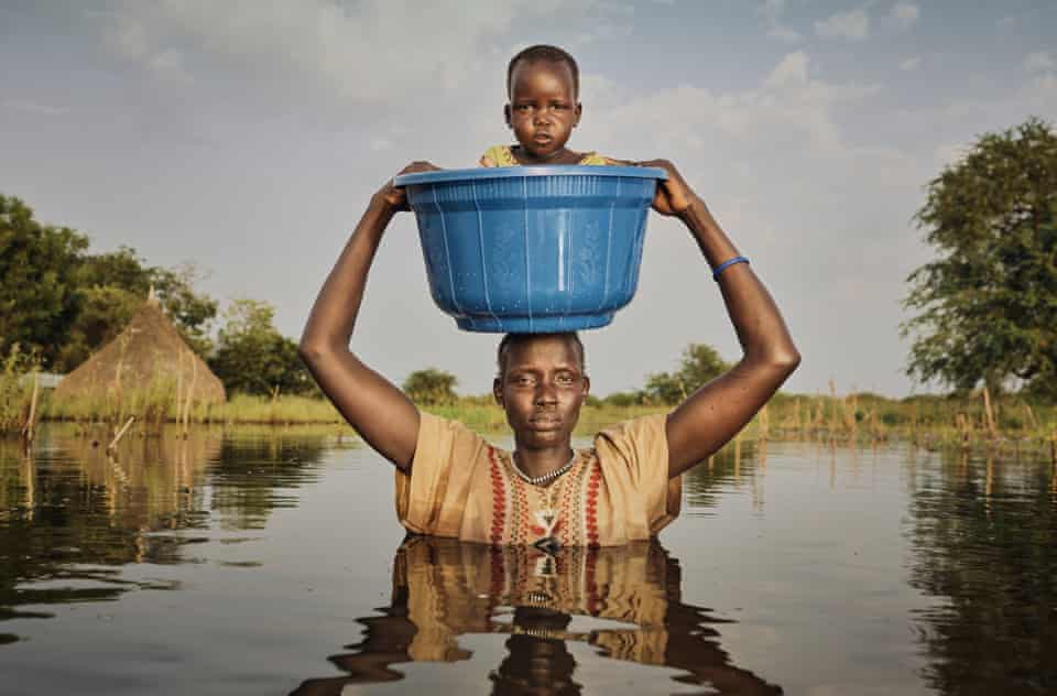 Nyalong Wal, 36, carries her daughter Nyamal Tuoch, 2, to dry land
