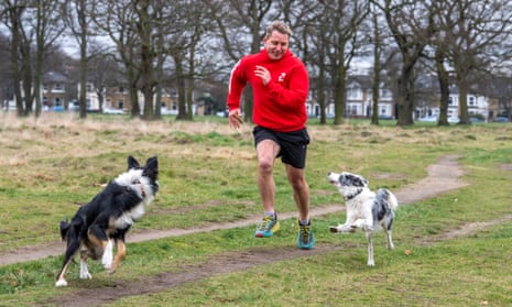 Aaron Robinson running in the park while two dogs leap about joyfully