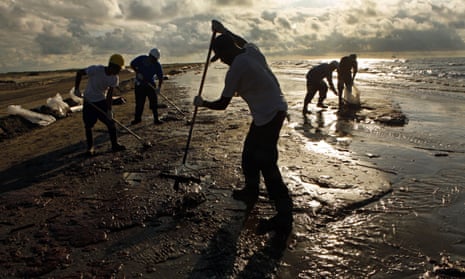 Workers hired by BP rake up globs of oil on the beaches in southern Louisiana.