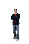 Andrew, wearing jeans and a black, diamond pattern sweater.