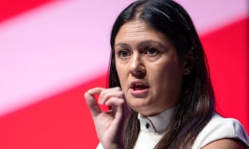 Lisa Nandy delivers a speech  in front of a red background