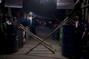 The presidential guard members sit in two rows, their spears leaning against their riot shields