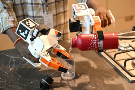 A person uses robot hands to pour water from a bottle into a glass
