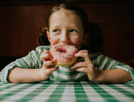 A child sitting at a table eating a doughnut