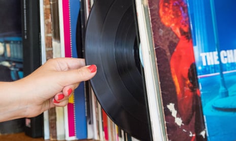 A woman's hand taking a vinyl record from a sleeve on a shelf