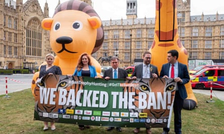 Five people hold up a banner reading ‘We backed the ban!’, with giant inflatables of a lion cub and a giraffe in the background.