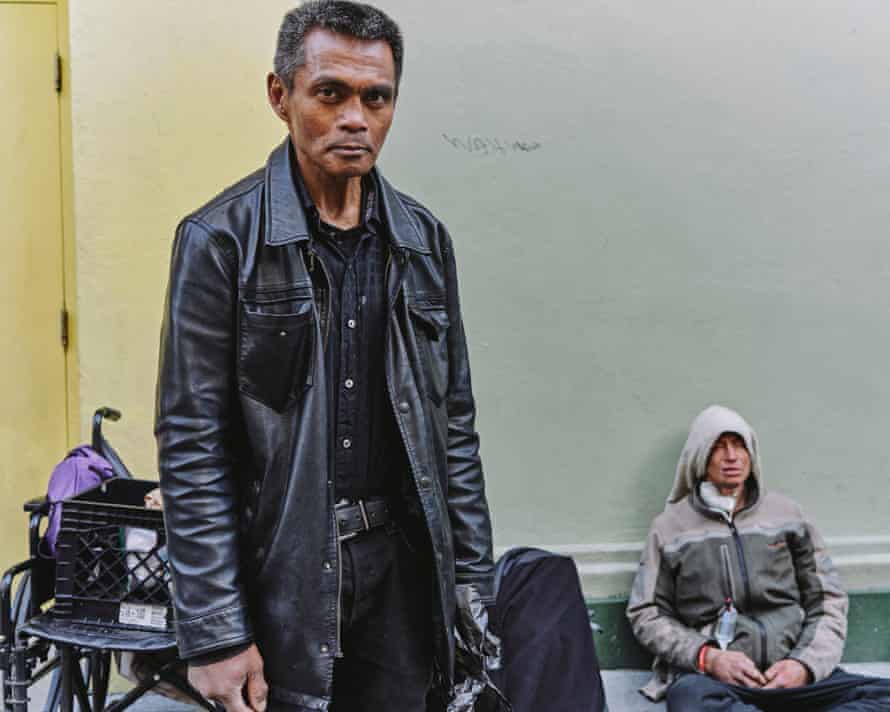 Fernandez in foreground with another person sitting against wall in background