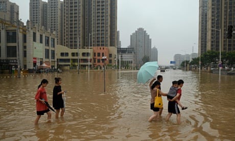 People wade across a flooded street in the city of Zhengzhou in China’s Henan province.