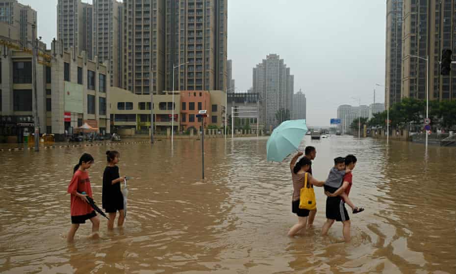 People wade across a street after heavy rains in Henan province, China, in July 2021.