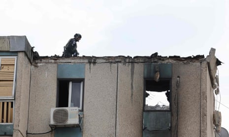 An Israeli emergency worker surveys the damage to a partially destroyed building following a rocket attack from the Palestinian Gaza Strip on the Israeli city of Tel Aviv.