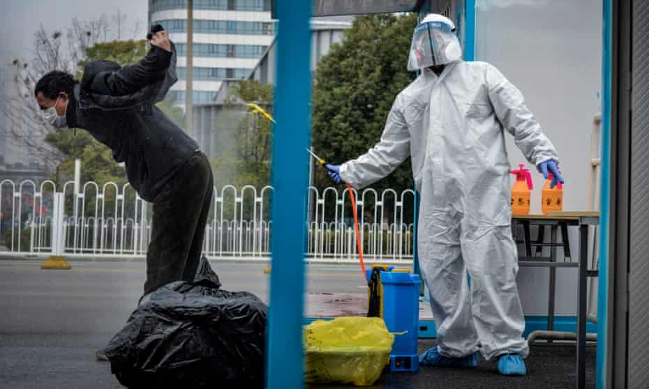 A man who recovered from Covid-19 is disinfected by medical staff as he leaves a hospital in Wuhan, China, in February 2020.