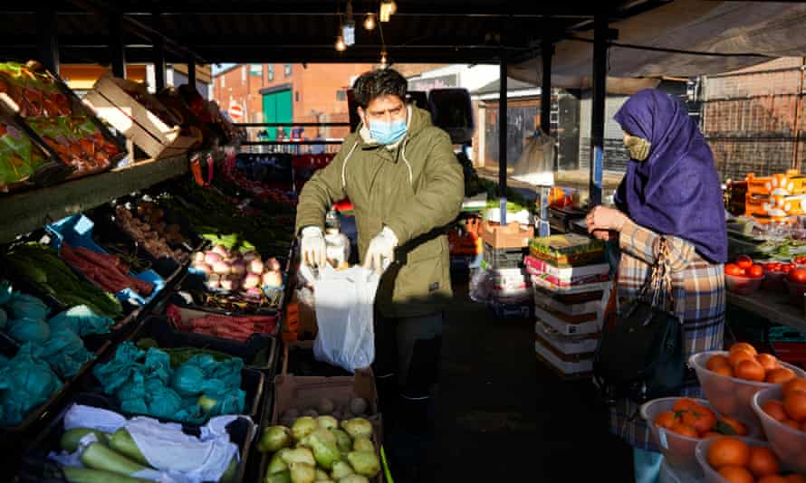 Saki Hussain helps a customer at Longsight market in Manchester.