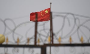 A Chinese flag behind razor wire at a housing compound in Yangisar, south of Kashgar, in China’s western Xinjiang region