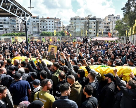 Mourners carry the flag-draped caskets of Hezbollah members killed in southern Lebanon during their funeral in the Kafaat area in Beirut’s southern suburbs
