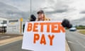 Amanda Gearing outside an Amazon warehouse in a hi-vis jacket holding up a giant sign saying 'Better pay'