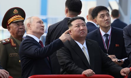 Vladimir Putin points while standing next to Kim Jong-un